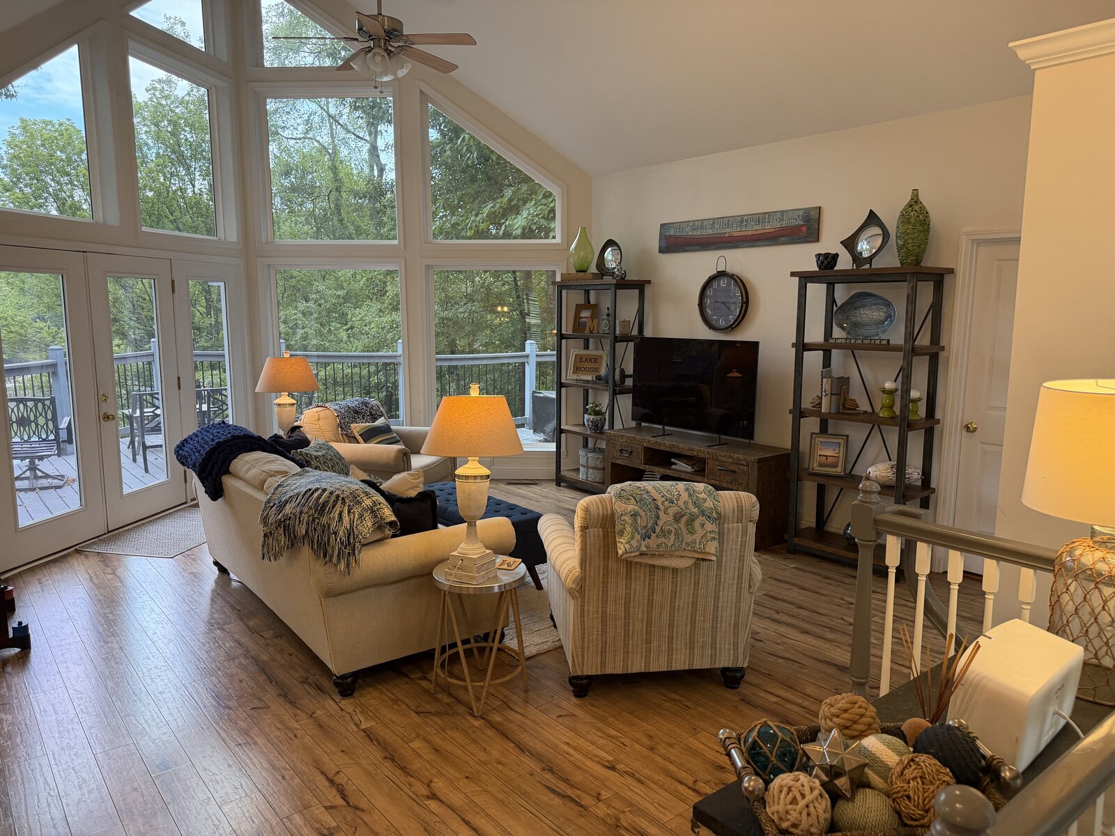 Renovated lake-house great room with a wall of vaulted windows over the deck, cream sofas, and layered blue-and-white accents