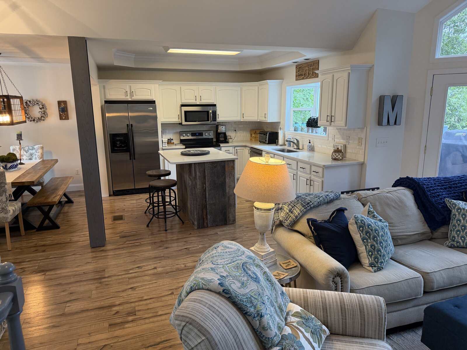 Kitchen after renovation — crisp white cabinetry, subway tile, and a reclaimed-wood island with counter stools