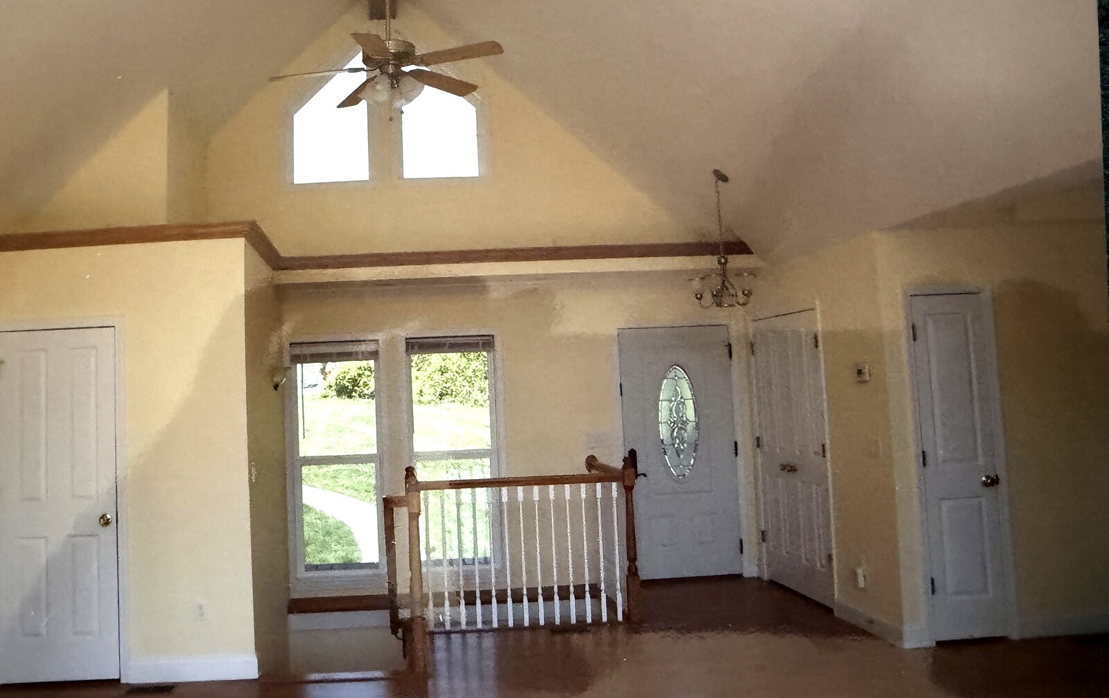 Entry before renovation — a closed-off landing with yellowed walls, a plain rail, and a leaded-glass front door