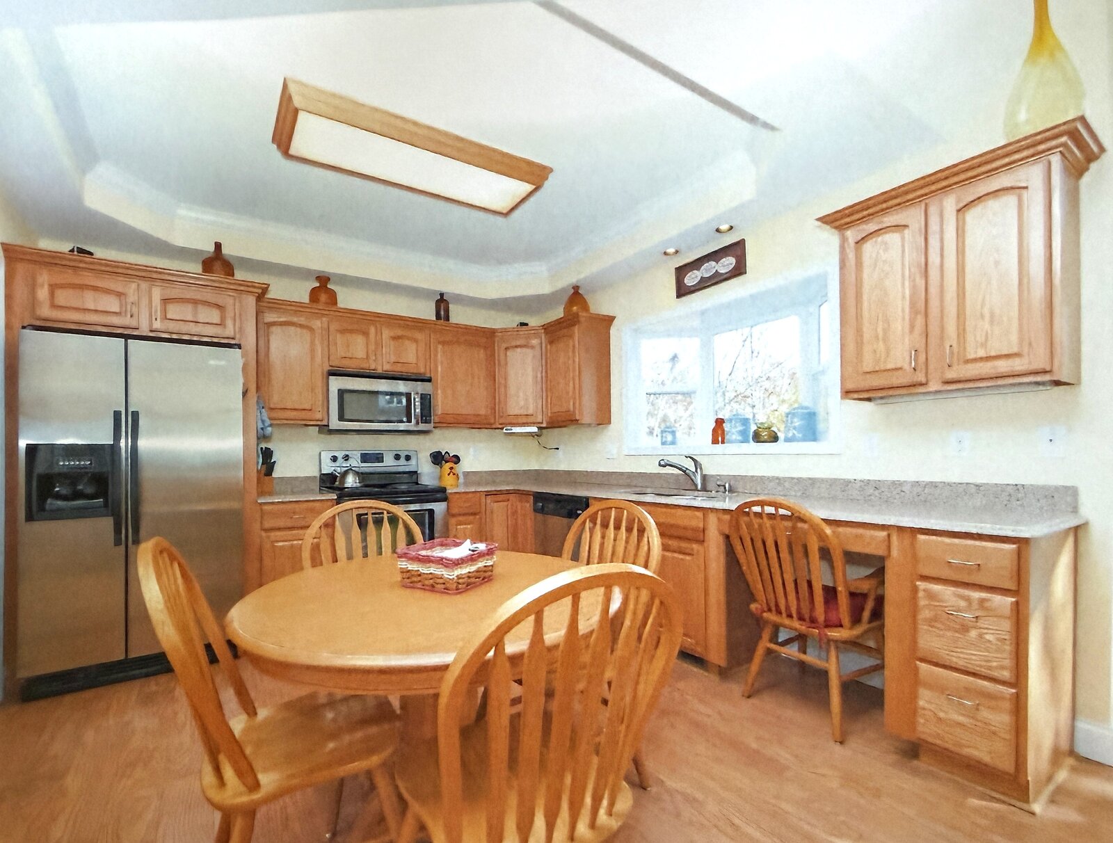Kitchen before renovation — honey-oak cabinetry, a boxed fluorescent light, and an oak dinette set