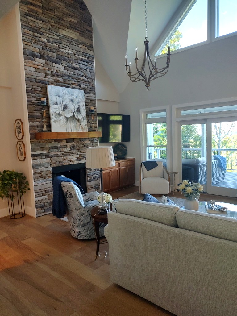 Two-story stacked-stone fireplace with a floral canvas and iron chandelier in a mountain great room