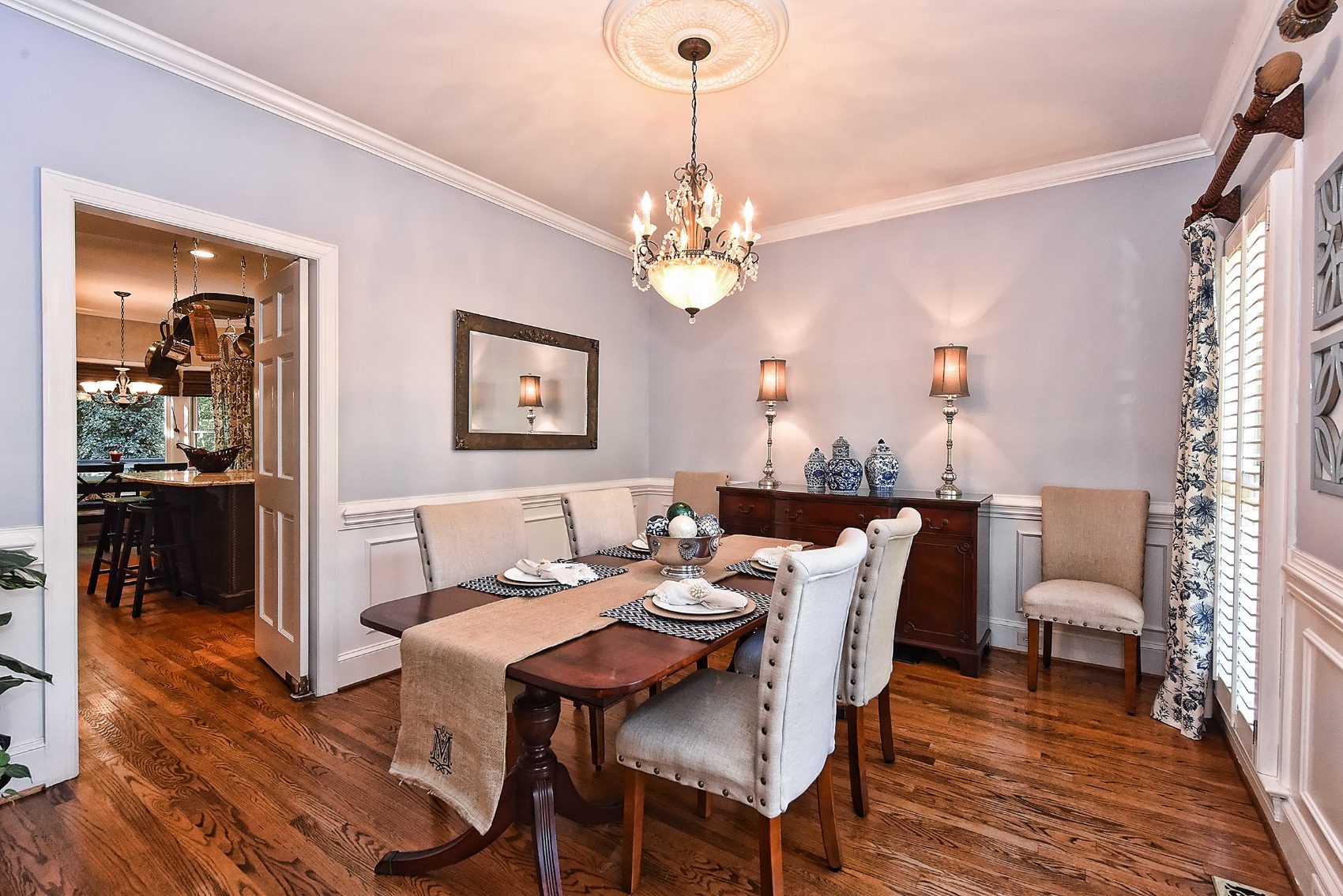 Formal dining room with chandelier, wainscoting, and a mahogany table set for dinner