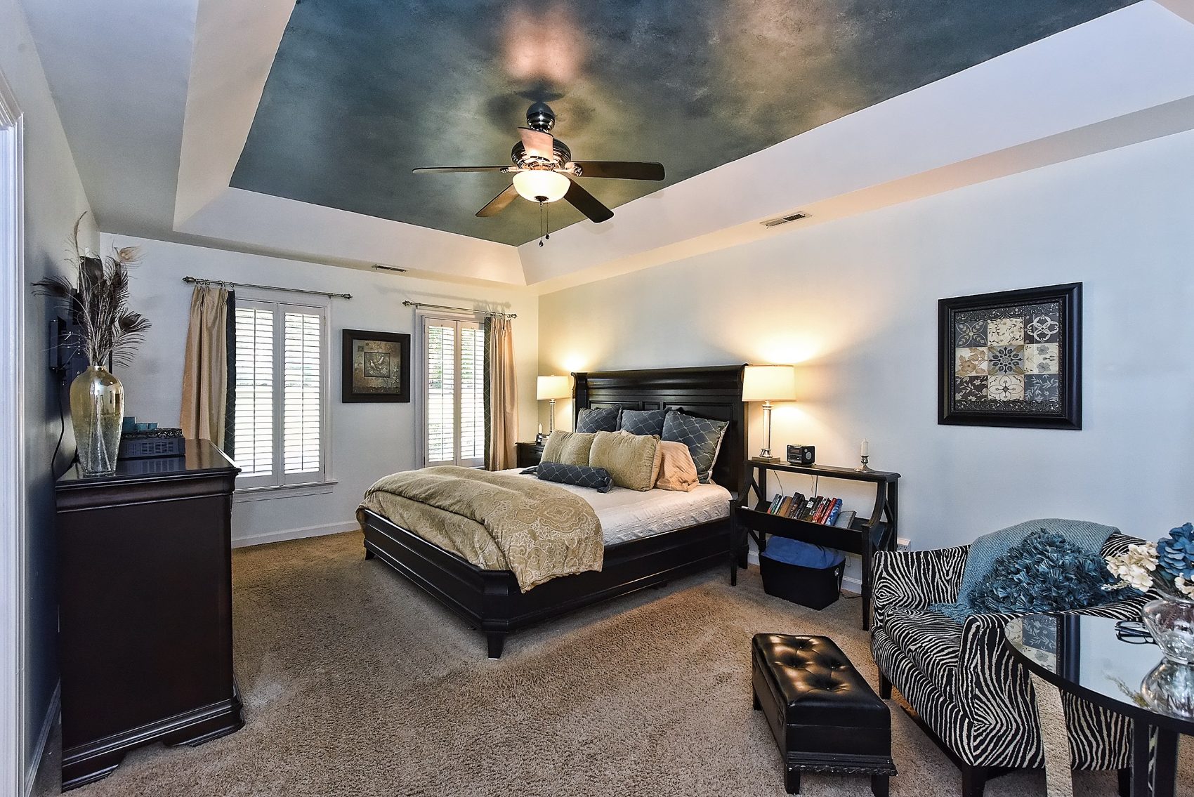 Primary bedroom with a hand-finished metallic tray ceiling and dark wood sleigh bed
