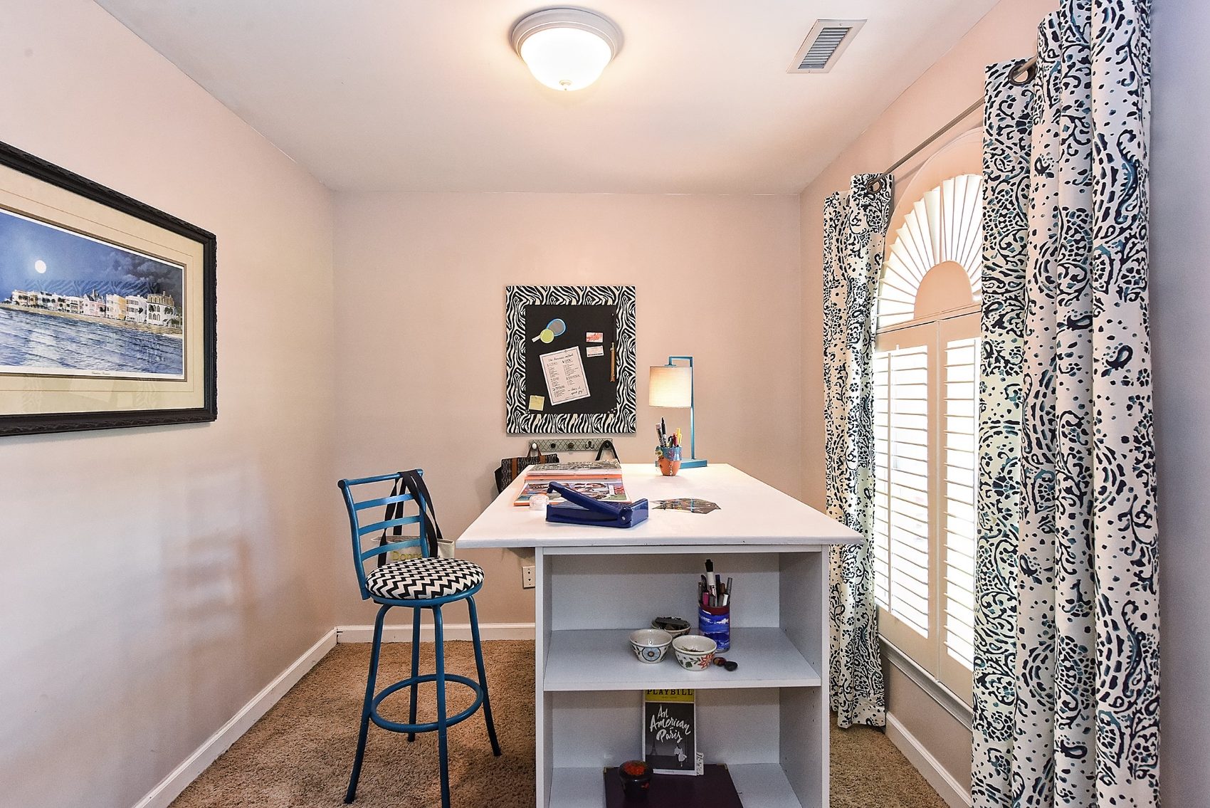 A cheerful craft studio with patterned drapery and a personal workspace